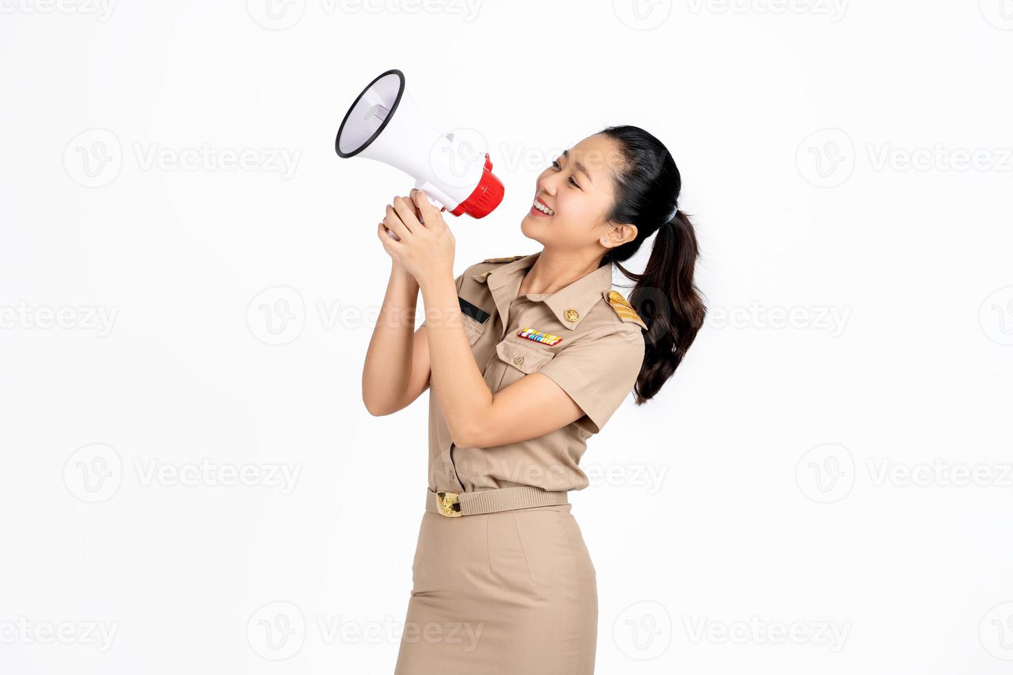 hermosa maestra asiática sobre fondo blanco aislado sosteniendo un megáfono y sonriendo a un lado foto