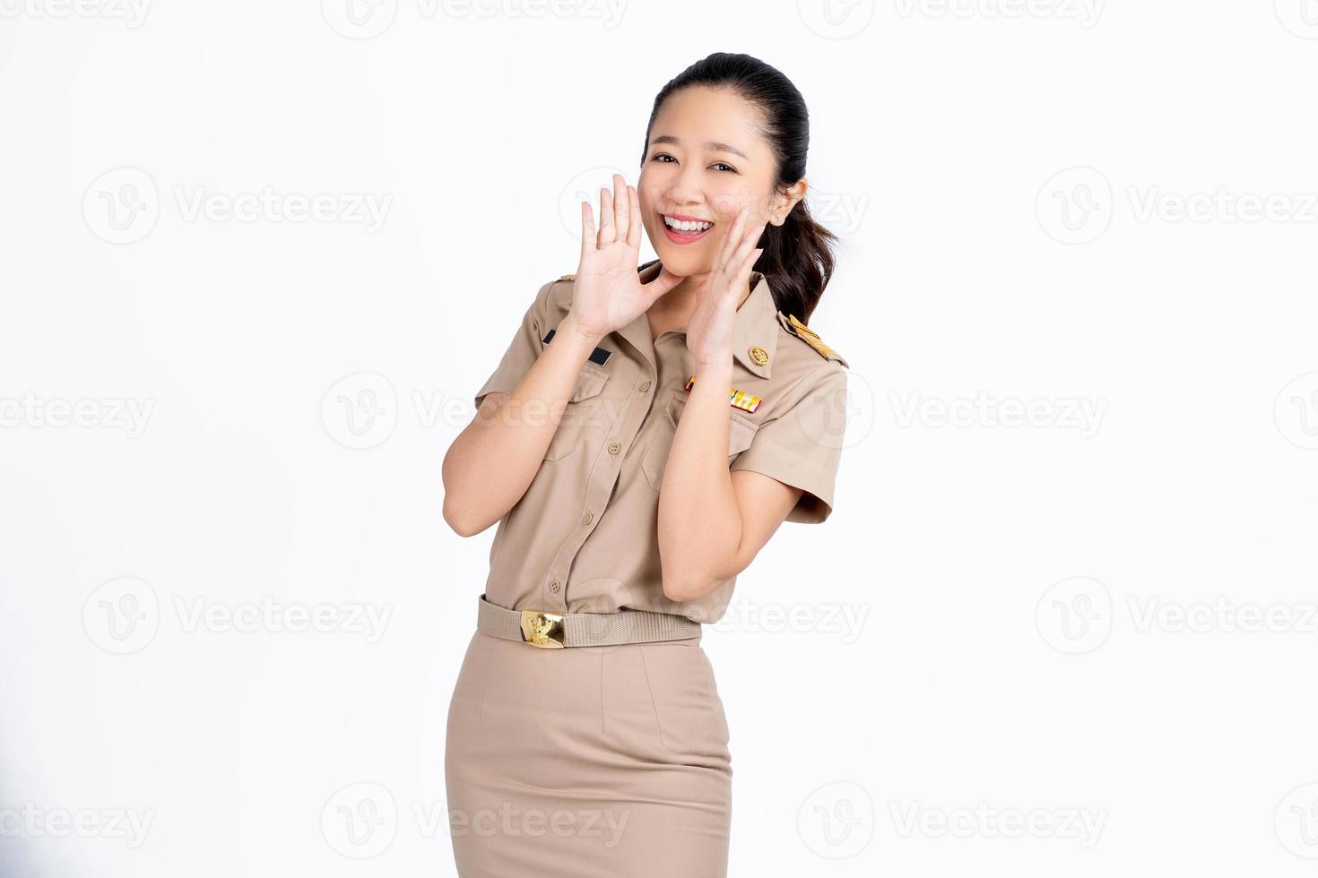 Young teacher girl of Asian ethnicity in university uniform open mouths raising hands screaming announcement isolated on white background. photo