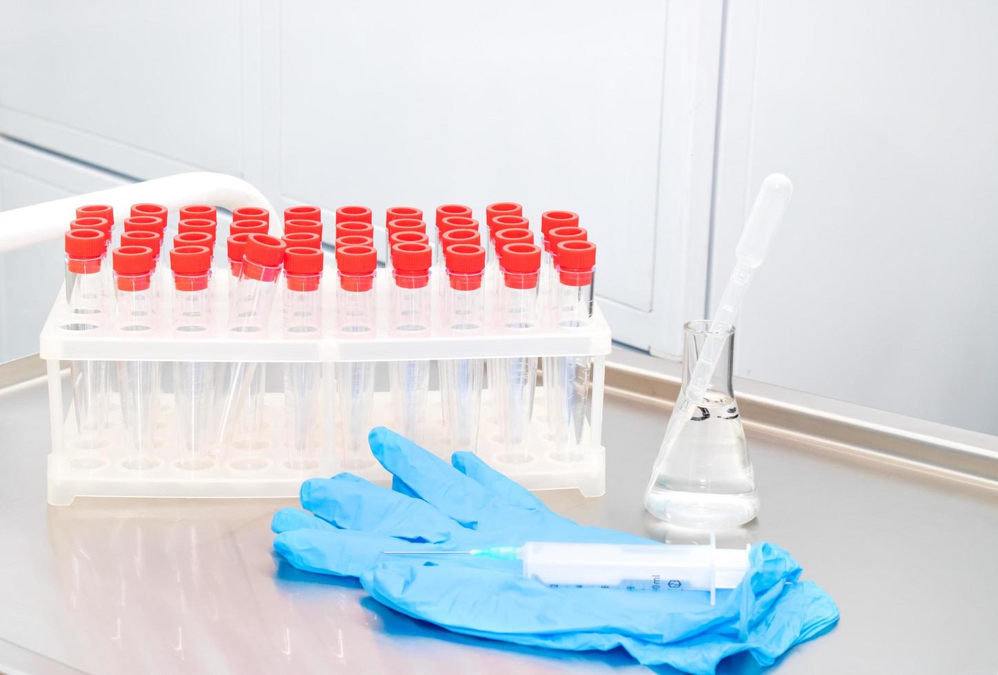 on the treatment table a rack with test tubes for analysis, gloves, syringe photo