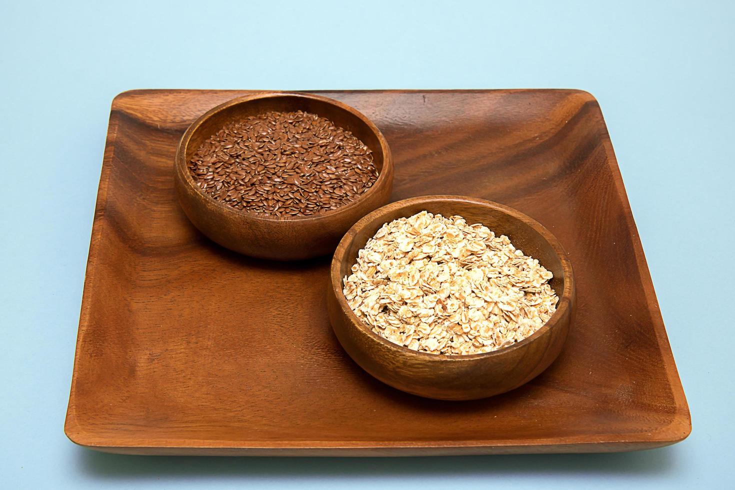 Flax seeds and oatmeal in a wooden bowl on a wooden tray photo