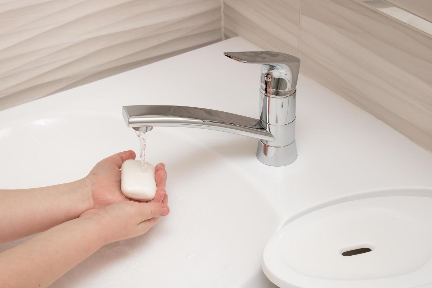 the child washes his hands with soap and water photo