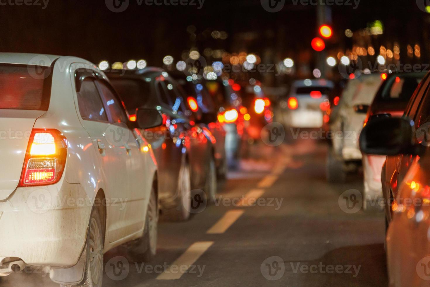 fila de autos parados frente al semáforo por la noche foto