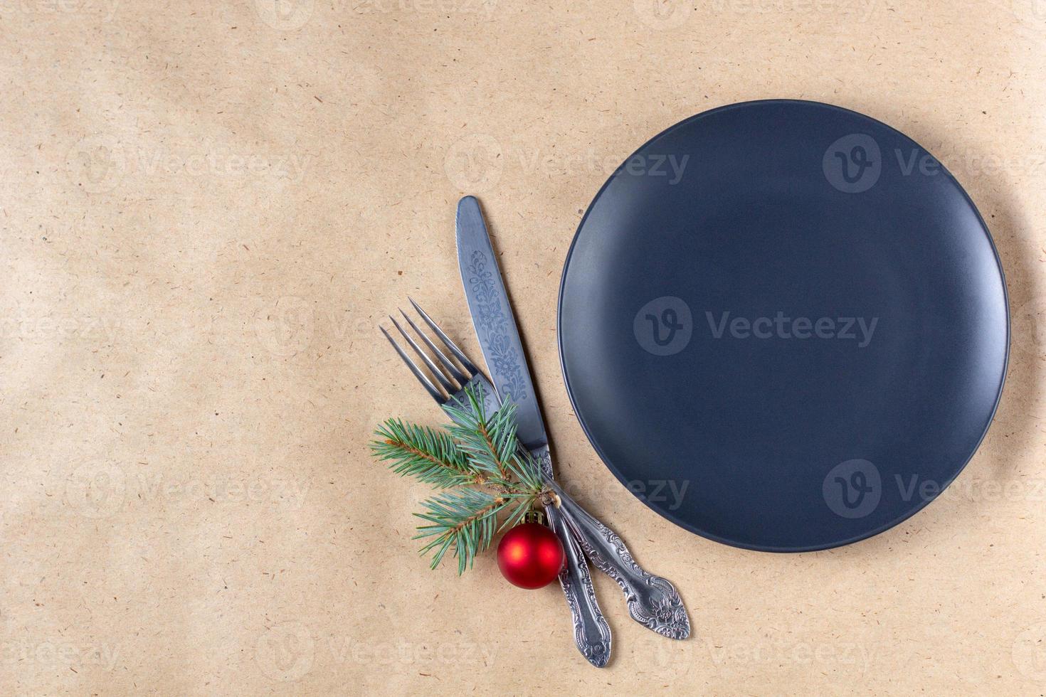 Holiday table setting with branch of christmas tree, empty plate and decorations. New year flat lay food concept photo