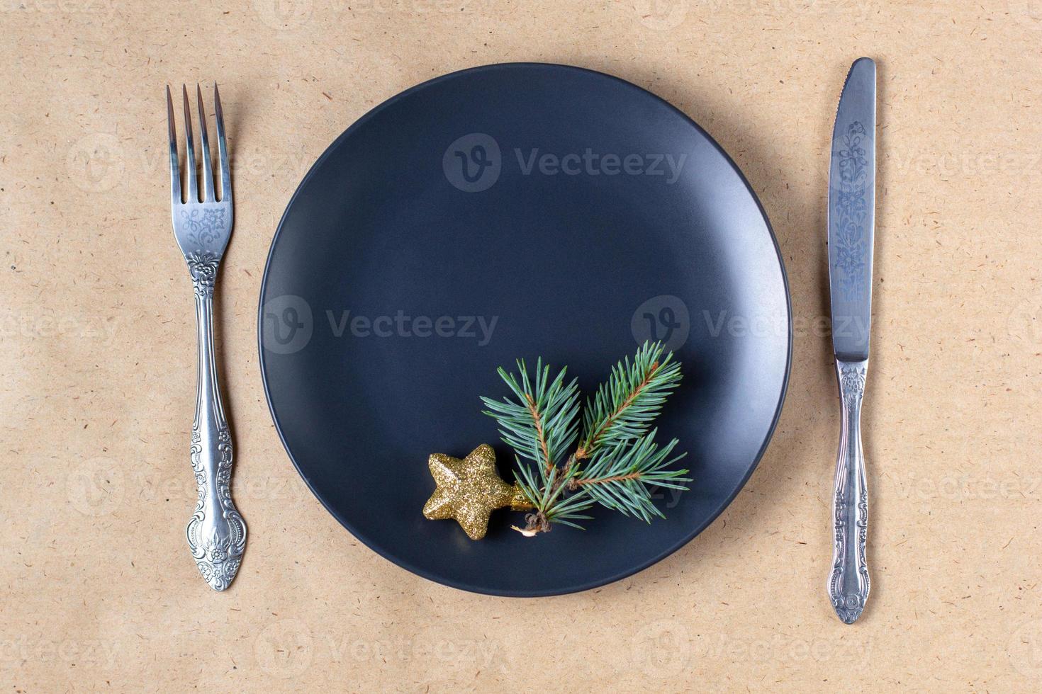 Holiday table setting with branch of christmas tree, empty plate and decorations. New year flat lay food concept photo