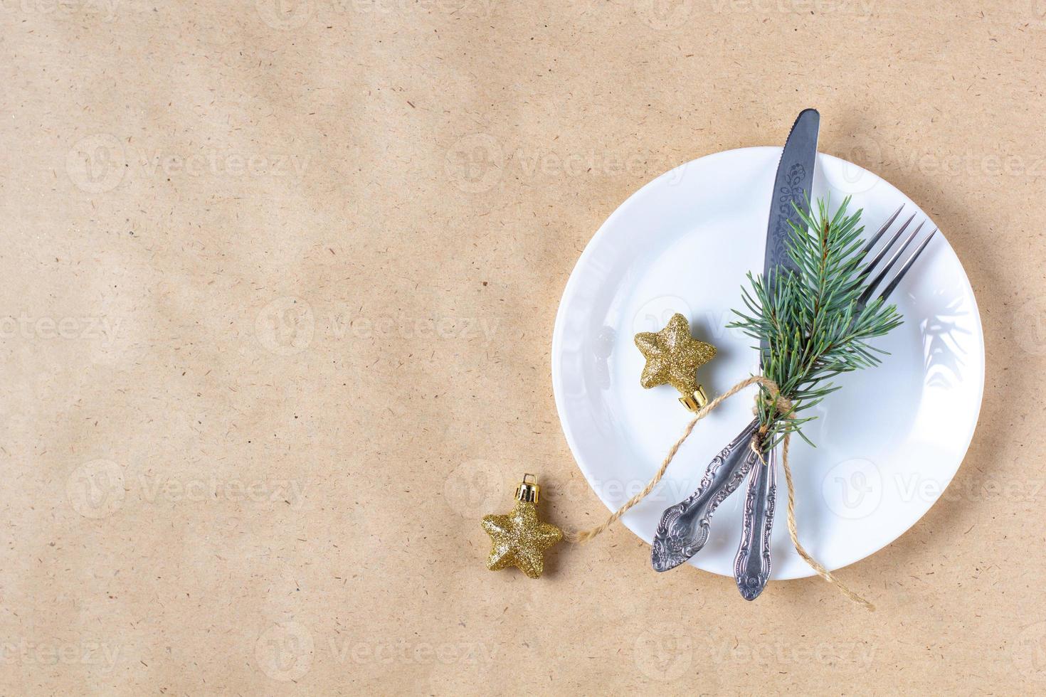 Holiday table setting with branch of christmas tree, empty plate and decorations. New year flat lay food concept photo