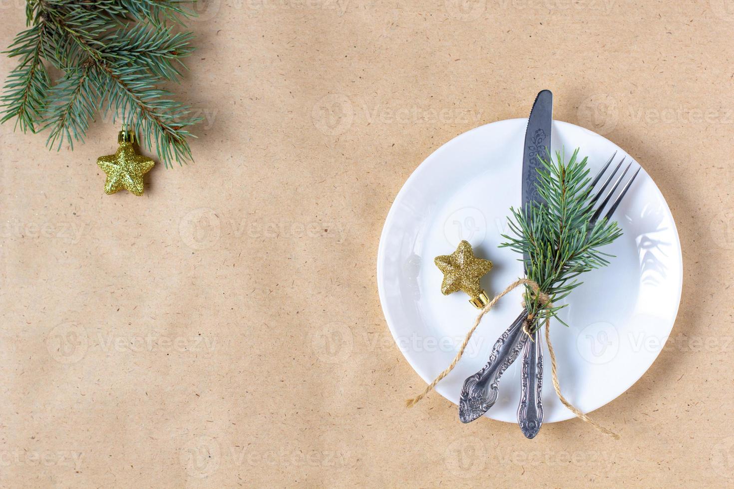 Holiday table setting with branch of christmas tree, empty plate and decorations. New year flat lay food concept photo
