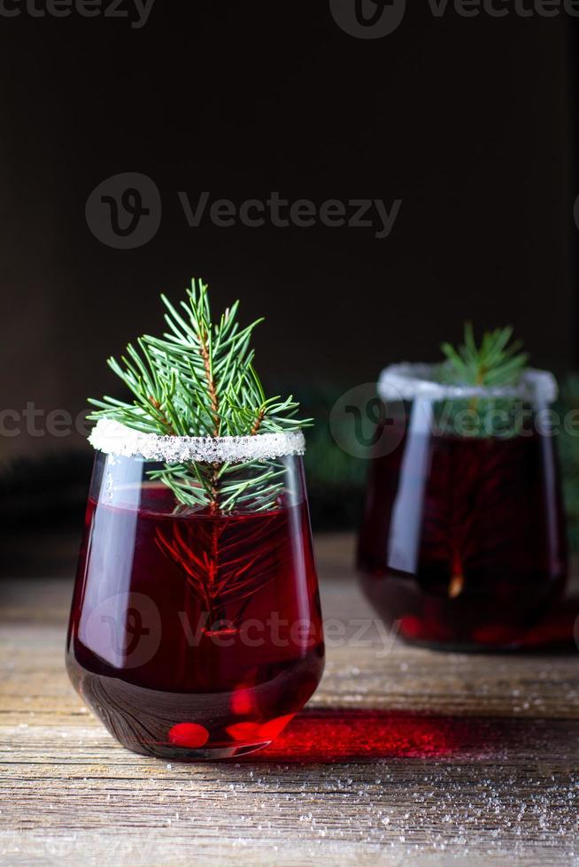 bebida roja de arándano decorada con ramas de abeto, bayas y azúcar. vino caliente caliente de navidad foto