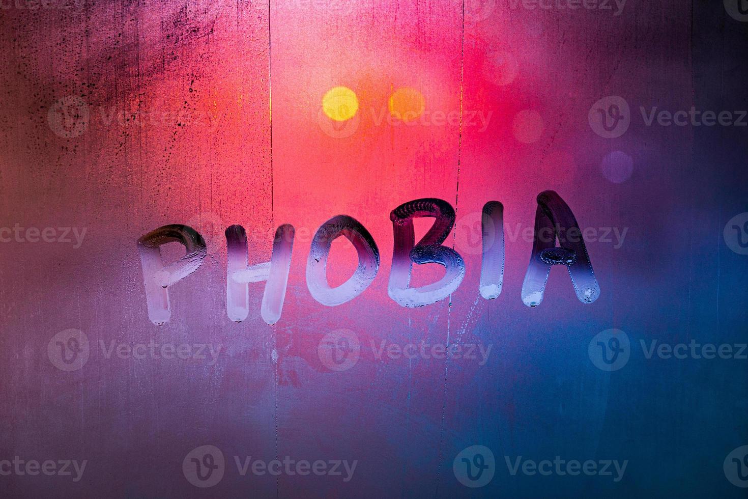 the word phobia handwritten on wet foggy window glass surface with red