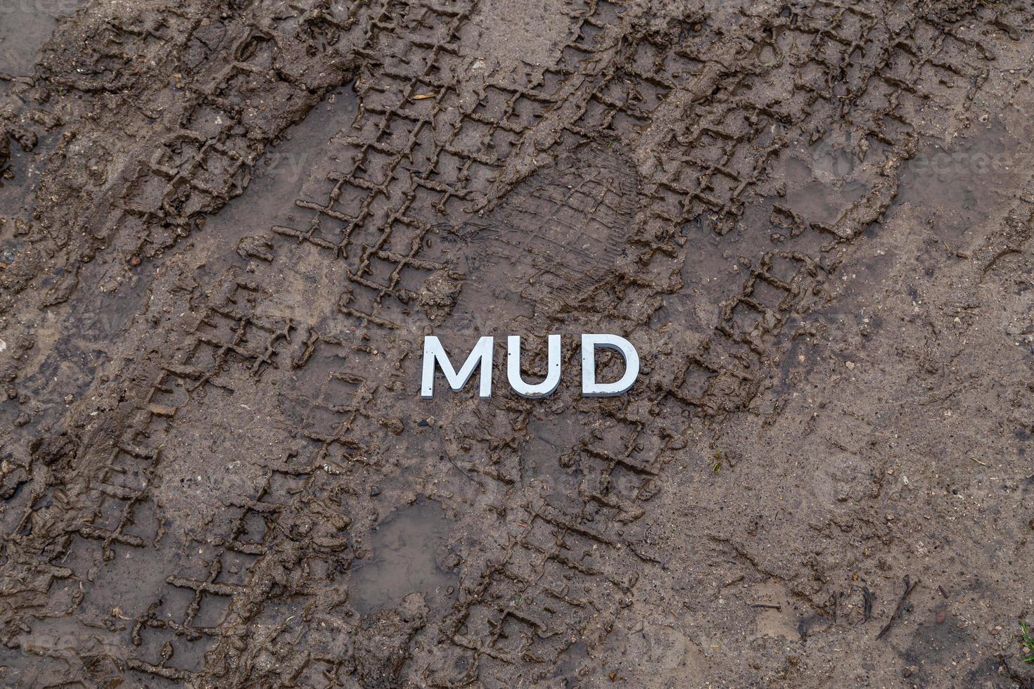 the word mud laid with silver metal letters on wet dirt surface photo