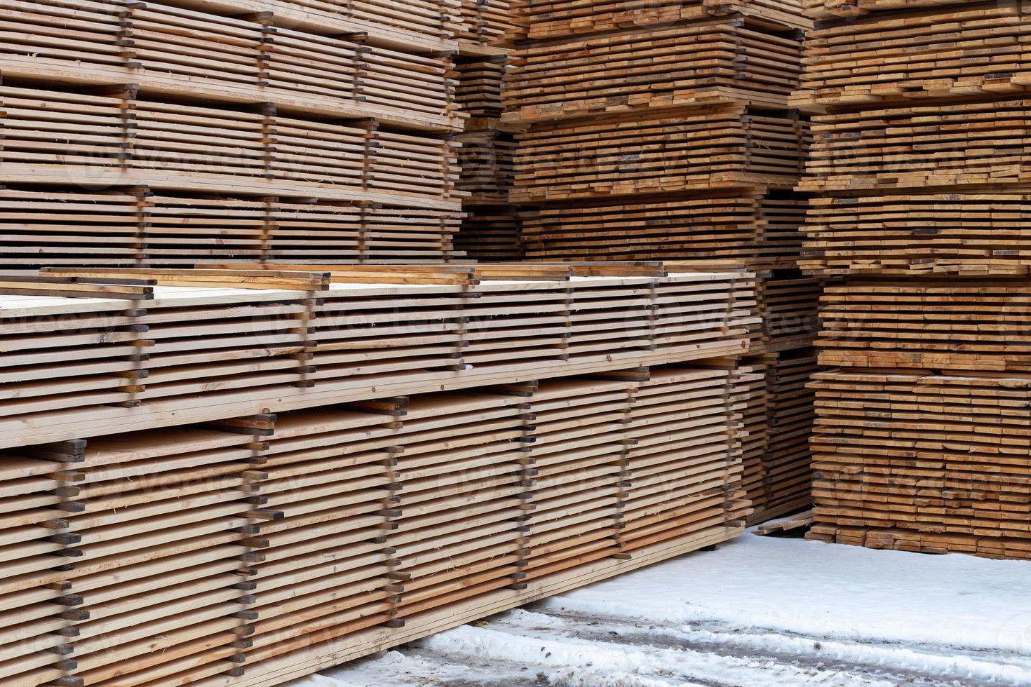 large stacks of wooden planks background with selective focus and linear perspective. Winter oudoor storage. photo