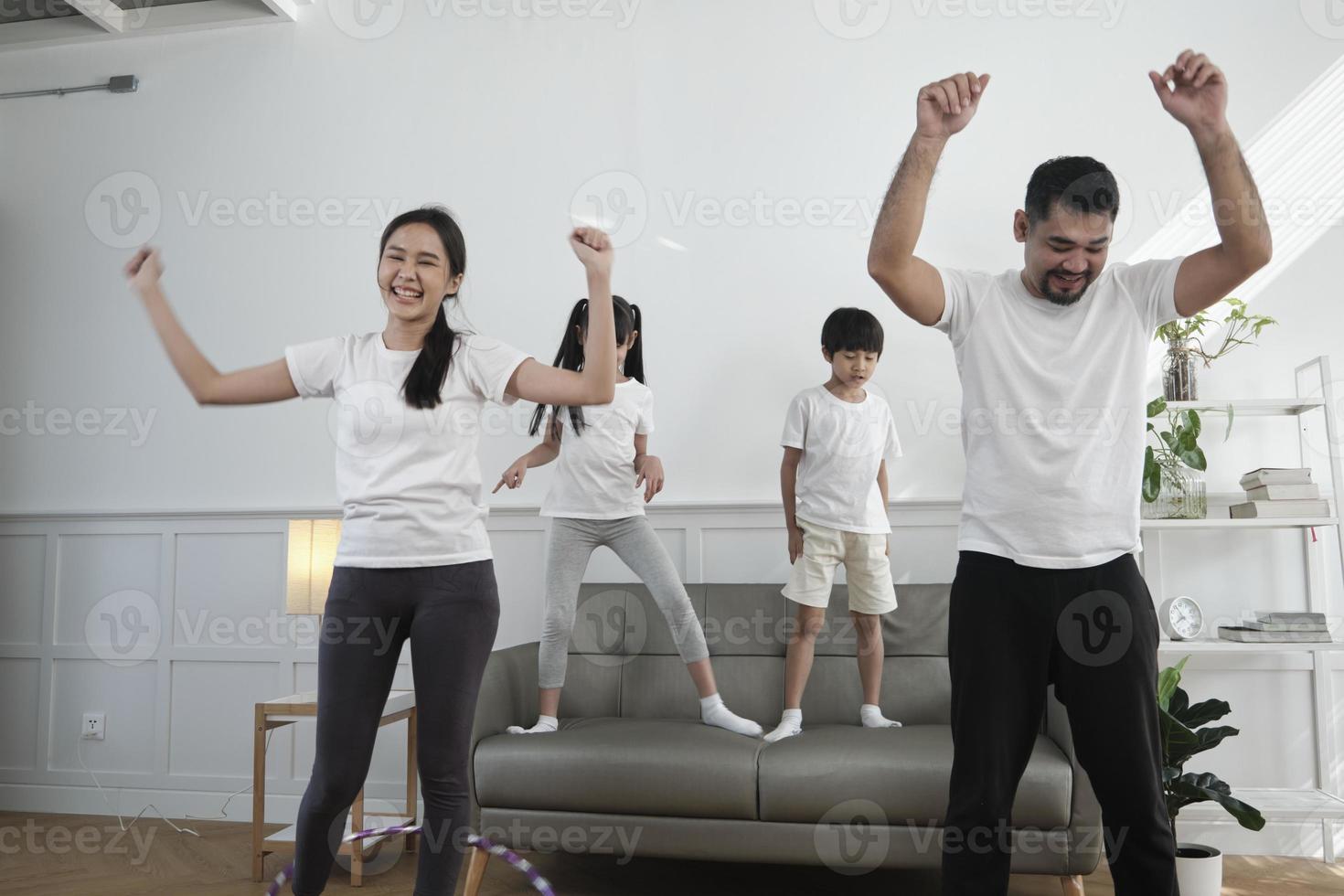 Happy wellness Asian Thai family, parents, and children are fun playing hula hoops together, fitness training and healthy exercise in white living room, domestic home lifestyle, and weekend activity. photo