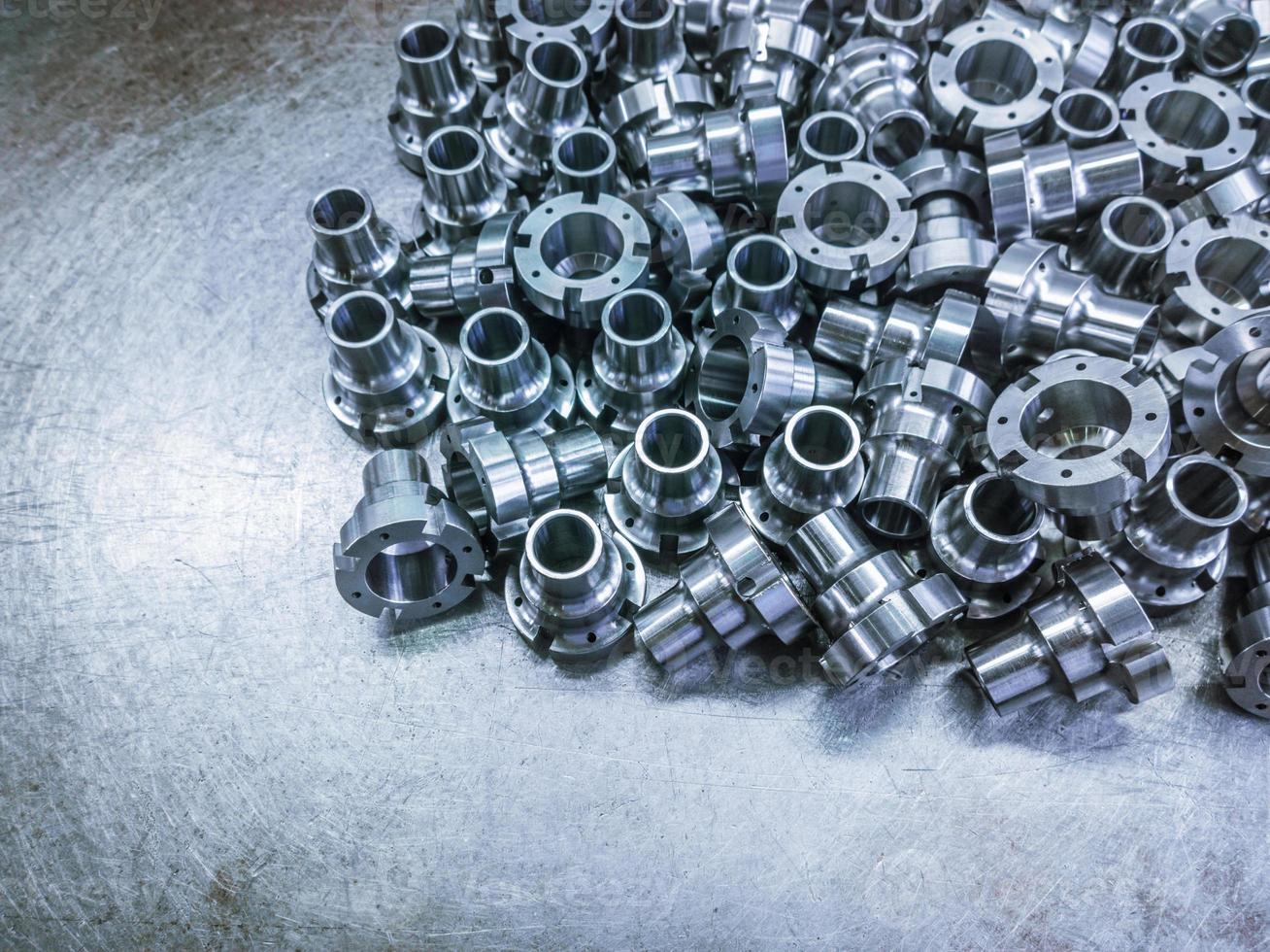 A pile of shiny steel parts after cnc turning and milling operations on steel sheet - close-up with selective focus. photo