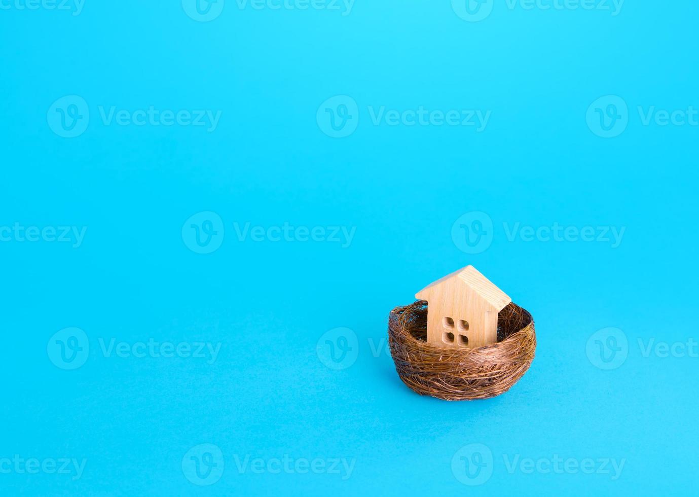 Figurine of a house in a birds nest. Home security concept, real estate insurance. Mortgage credit lending. Affordable housing for young families. Realtor services. Design and construction. photo