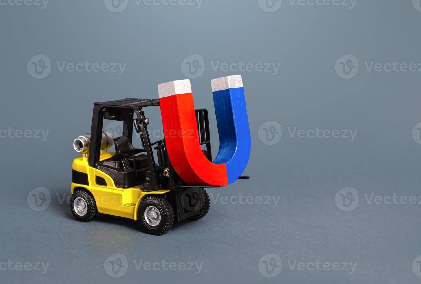 A forklift is carrying a big magnet. The concept of attraction and gravity. Attracting money and investments for startups. Increase profits and attract new customers. Salary, bonus, cashback. photo