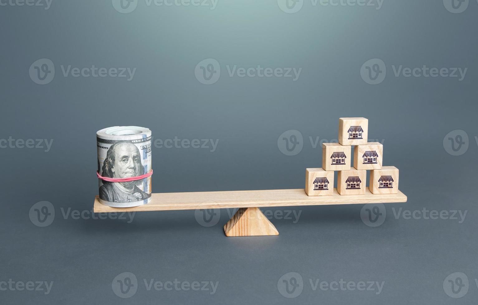 Blocks with business shop symbols and money dollars on scales. Franchising. Assessing value of a business empire. Calculation of income and taxes. Financial support for small businesses in crisis. photo