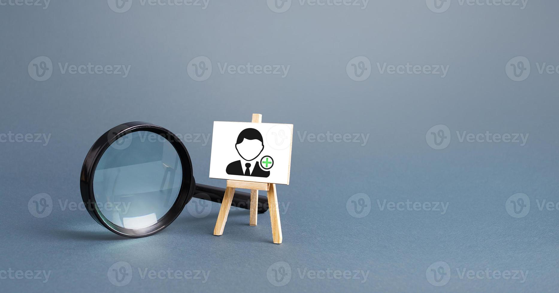 Magnifying glass and an easel with a new hired employee. Recruiting and HR management. Hiring new workers, staffing. Headhunters and Human Resources. Search for skilled specialists and professionals. photo