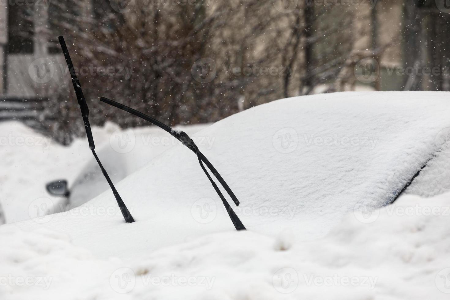 wipers sticking out of the snow coverd car at cloudy day light photo