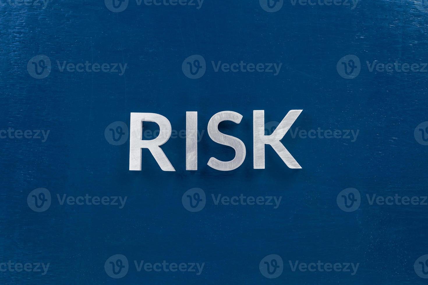 the words risk laid with silver metal letters on classic blue surface for stock market background photo