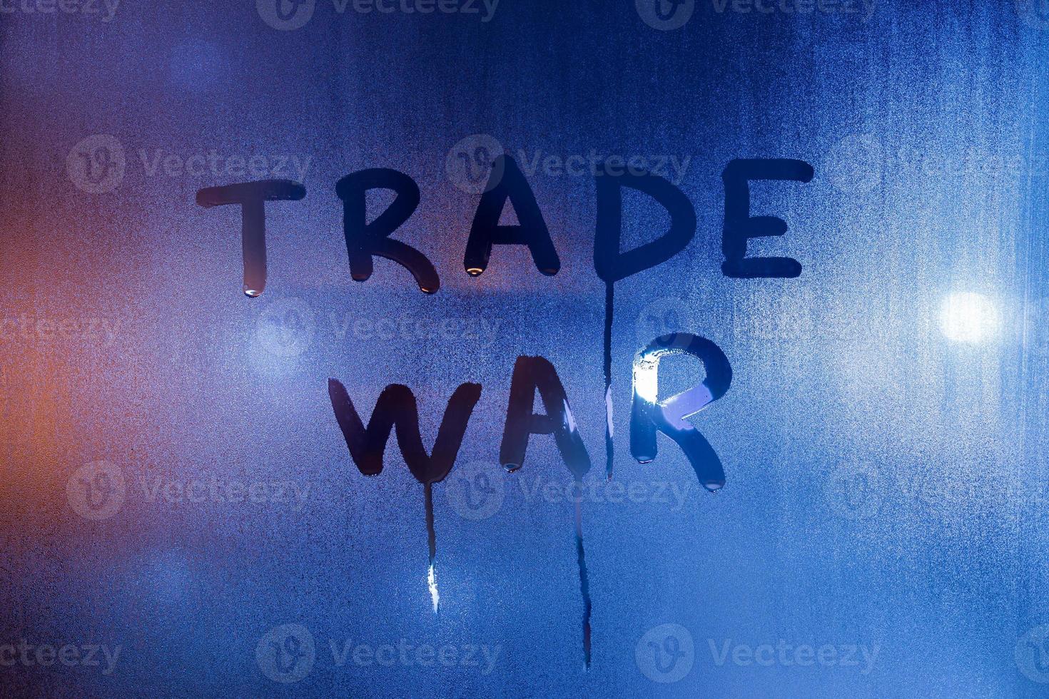 the phrase trade war handwritten on classic blue night wet window glass photo