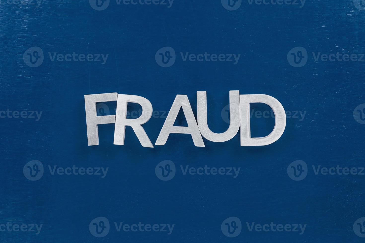 the word fraud laid with silver metal letters on classic blue painted board surface - wtih careless dodging order photo