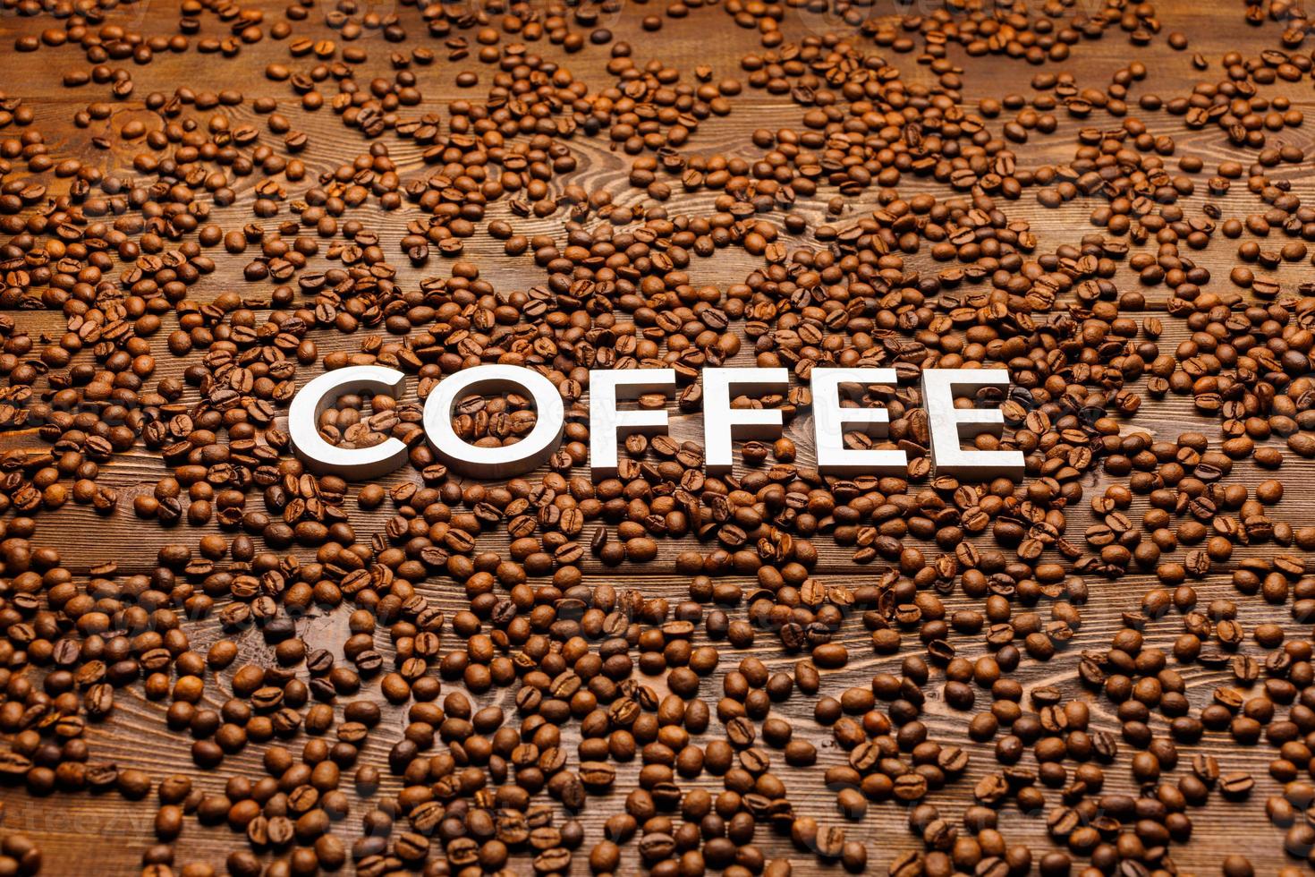 word coffee laid with silver letters on wooden surface covered with coffee beans photo