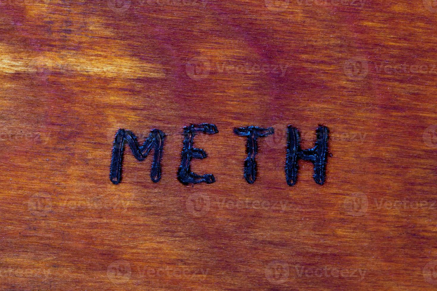 the word meth for Methamphetamine - burned by hand with woodburner on brown wood flat surface photo