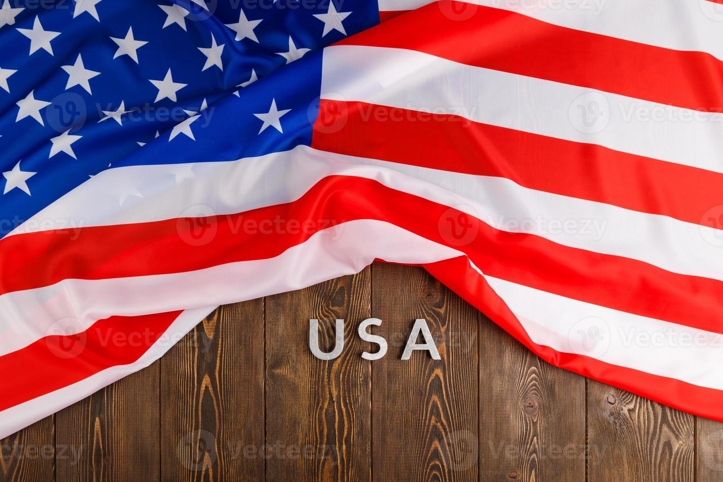 crumpled United States of America flag and with word USA laid with on flat textured wooden surface background photo