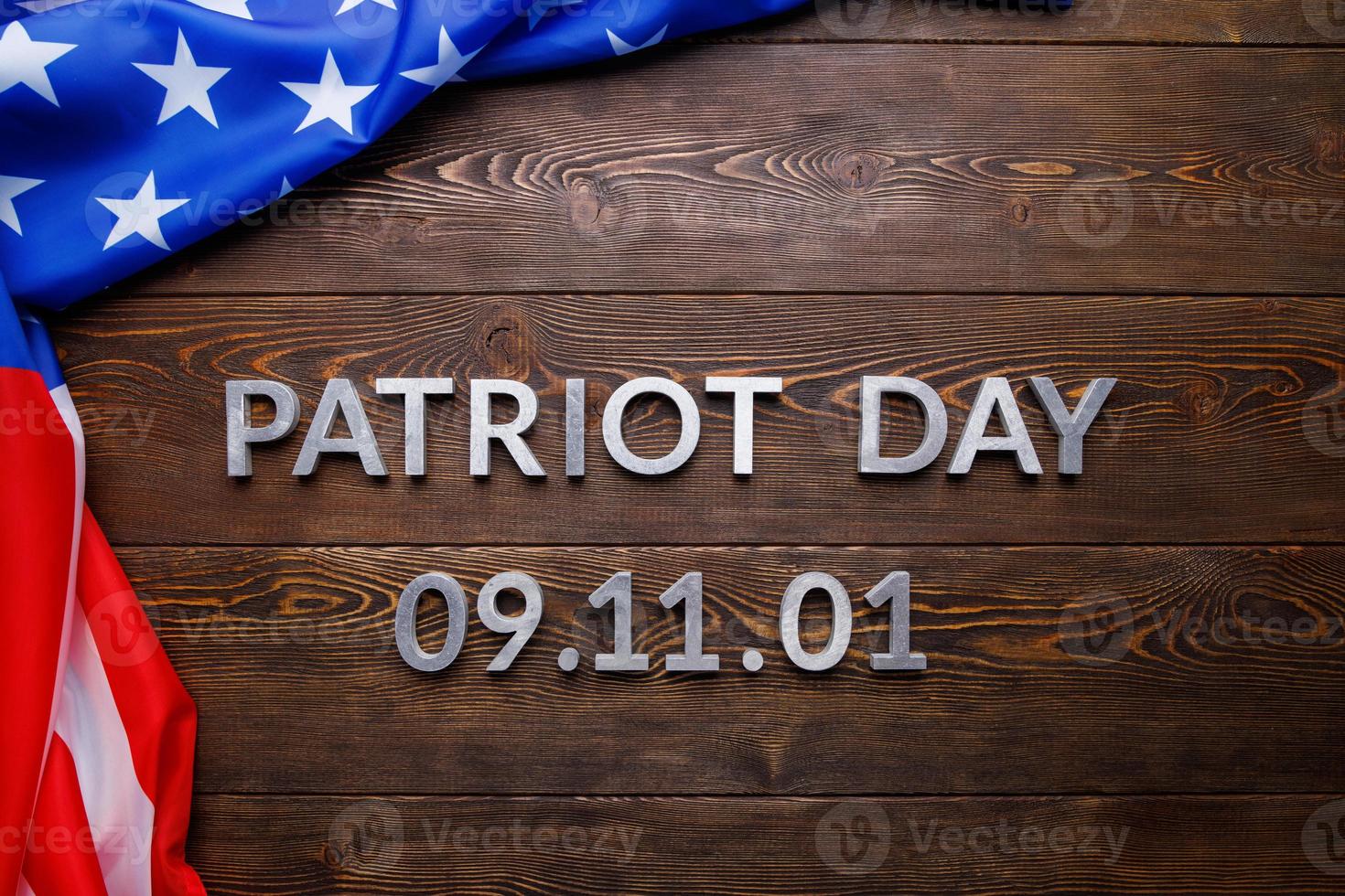 the words patriot day laid with silver metal letters on wooden board surface with crumpled usa flag photo