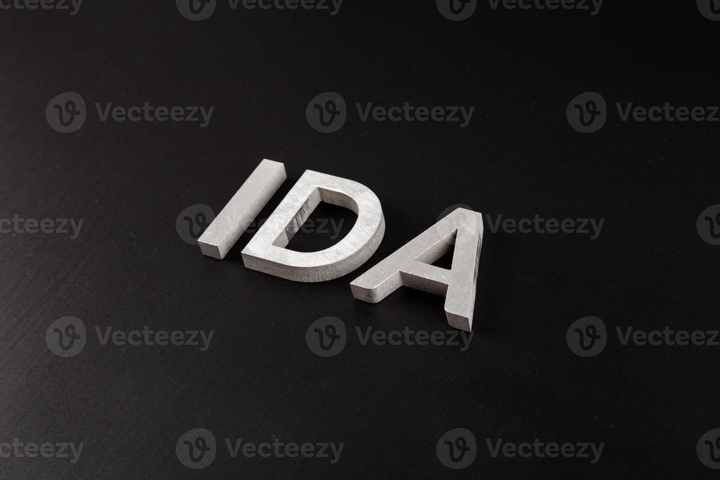 the word ida laid with silver metal letters over dry black matte surface photo