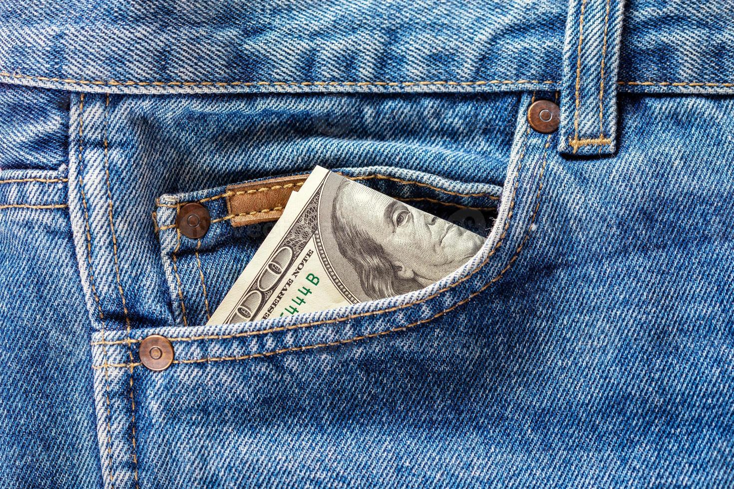 a hundred dollar banknote sticking out from front pocket of jeans photo