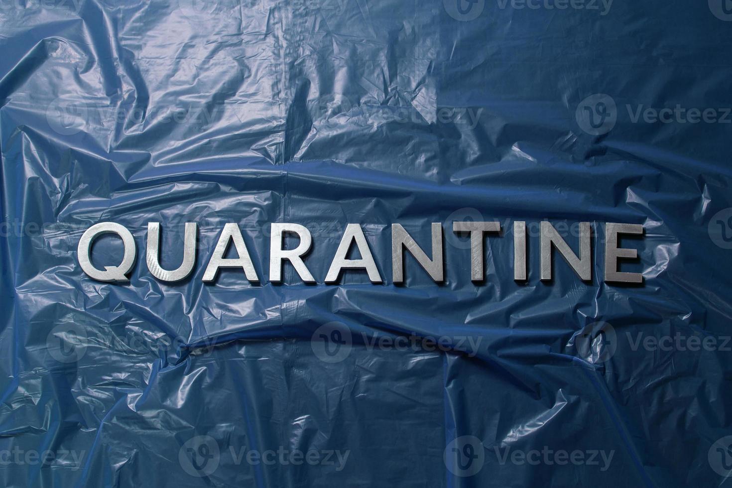 the word quarantine laid with silver letters on crumpled blue plastic film flat lay centered composition photo