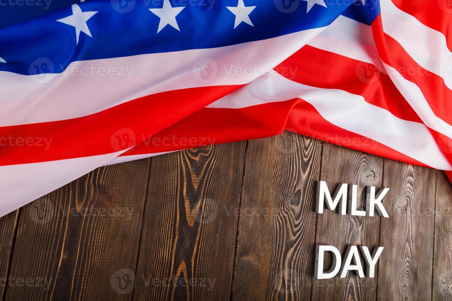 the word MLK day laid with silver metal letters on wooden surface with crumpled USA flag at upper side photo