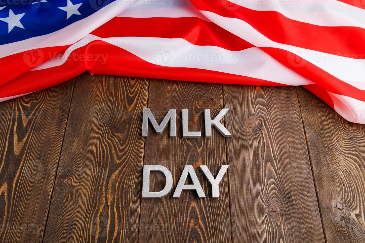 the word MLK day laid with silver metal letters on wooden surface with crumpled USA flag at upper side photo
