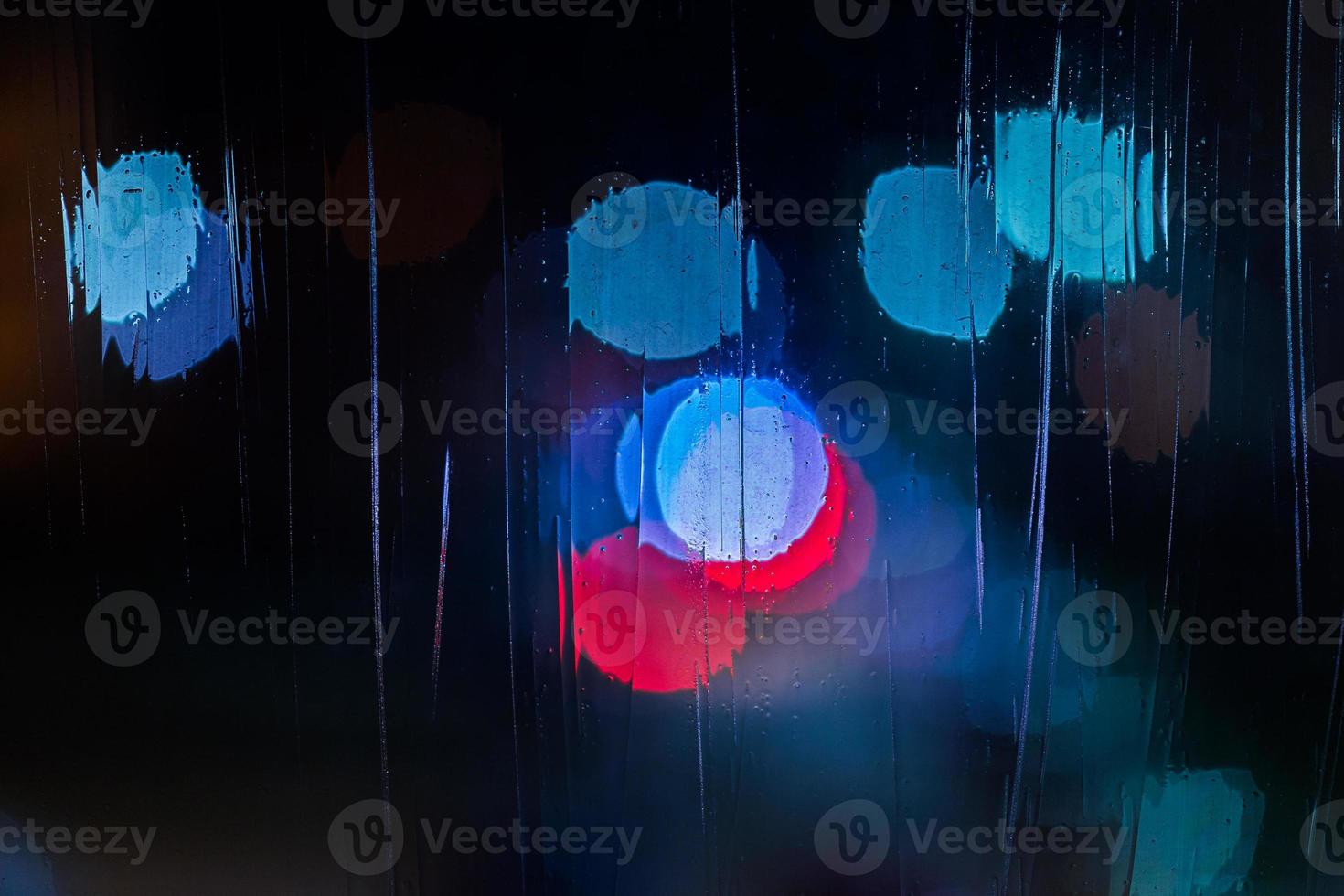 an abstract background night blue and red street lights bokeh through wet glass, close-up with selective focus photo