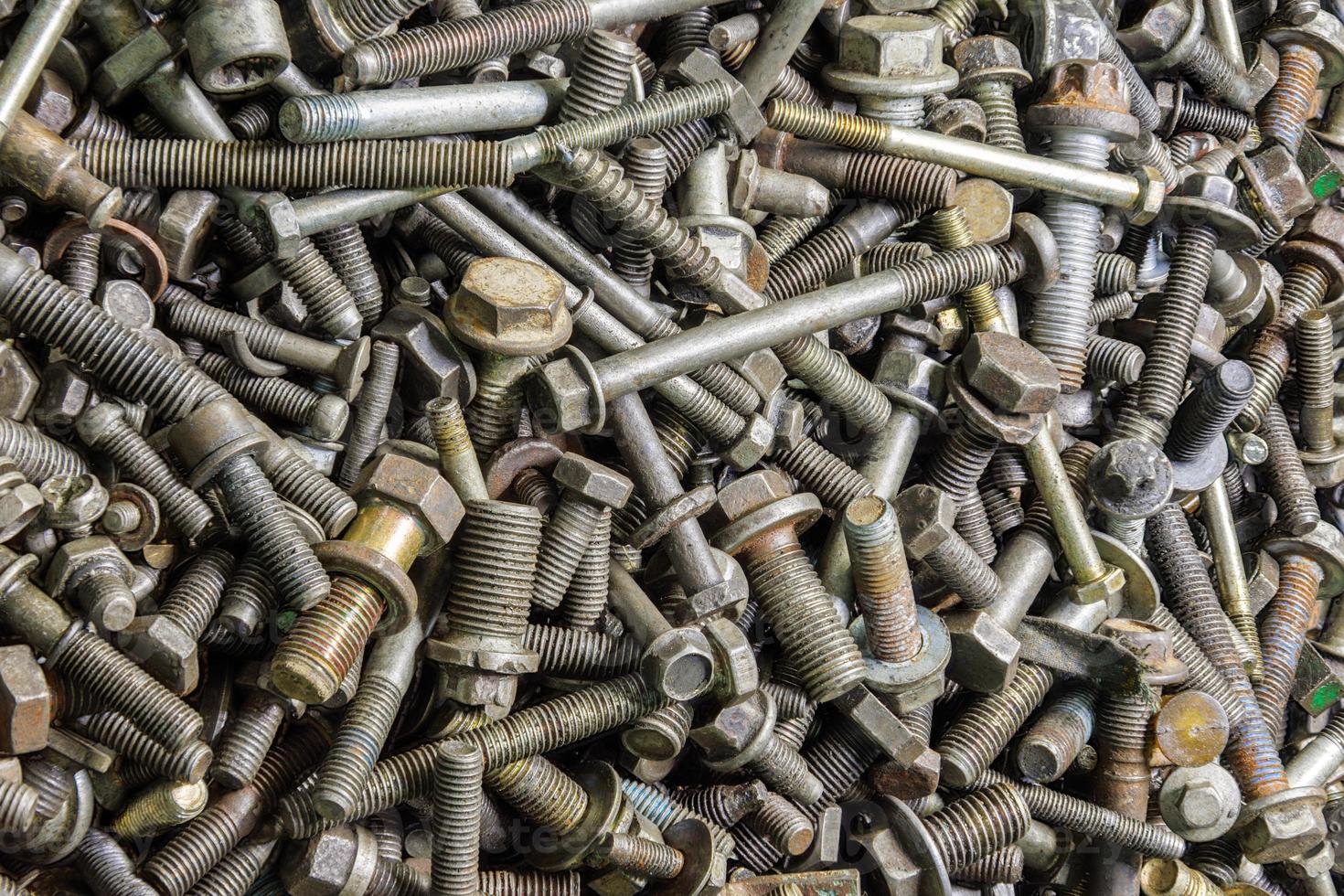 full frame background of used automobile bolts heap, old and dirty photo
