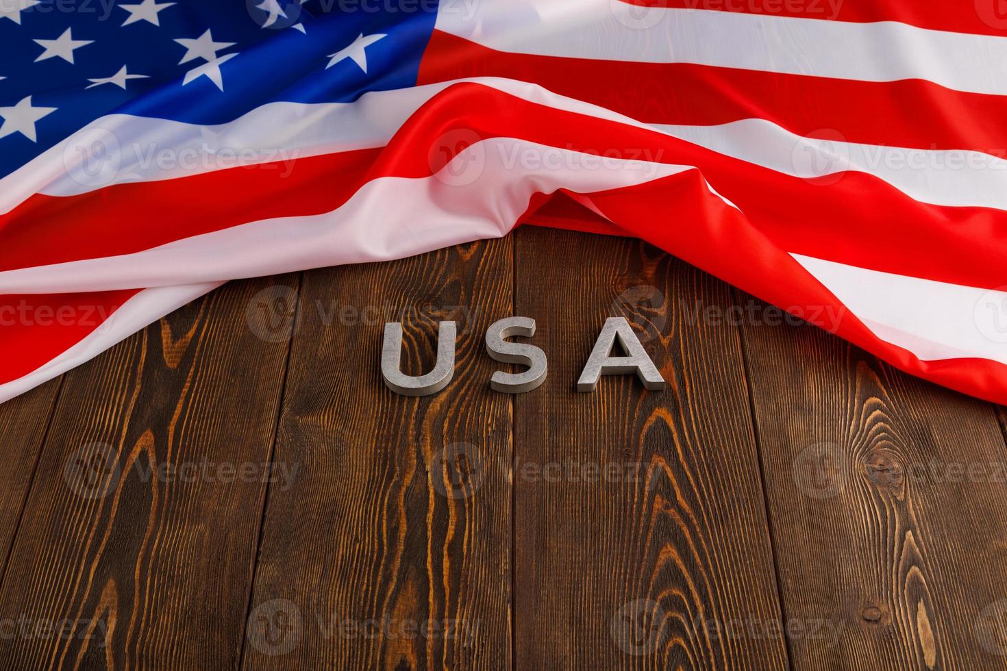 crumpled United States of America flag and with word USA laid with on flat textured wooden surface background photo