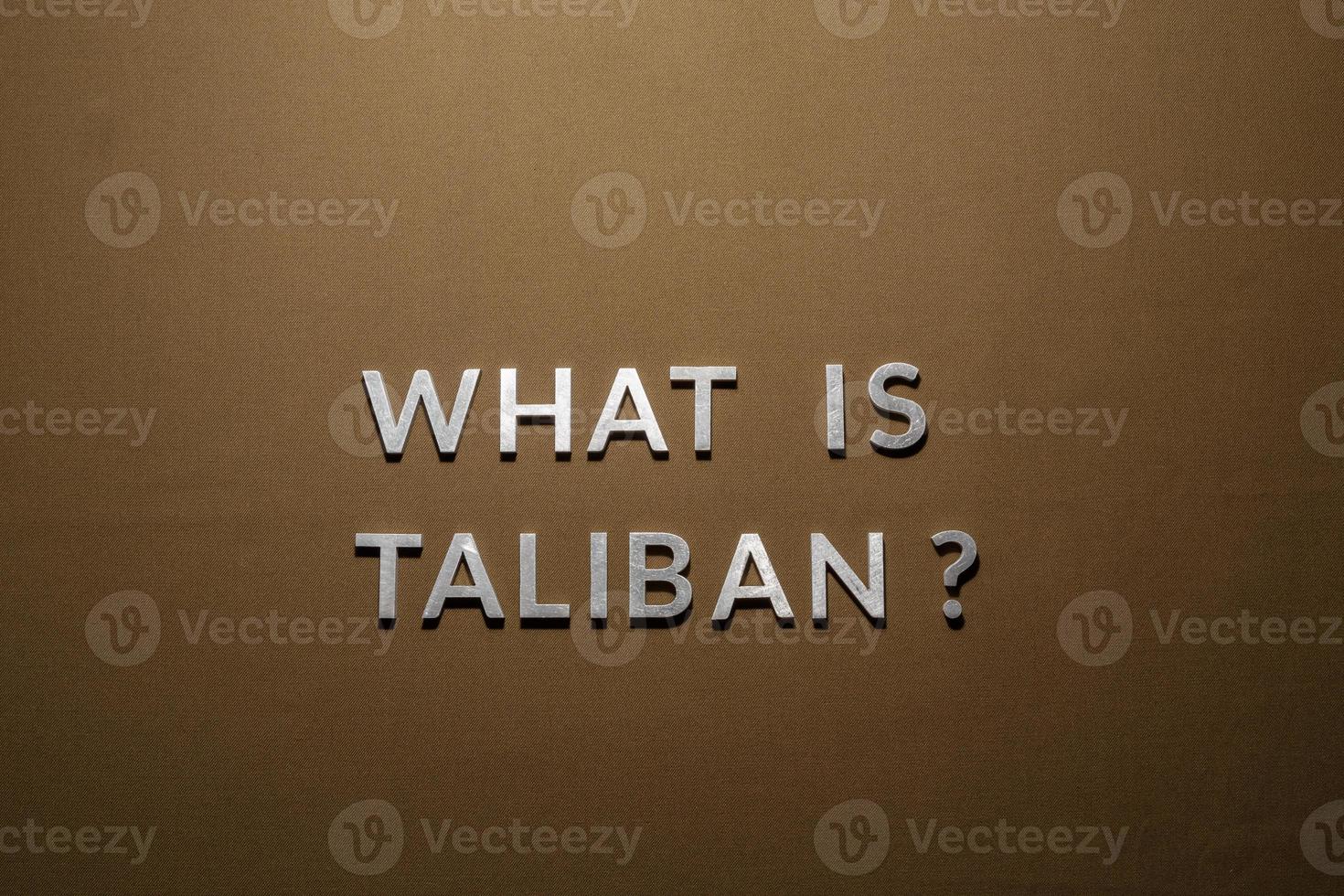 the question what is taliban laid with silver metal letters on rough tan khaki canvas fabric photo