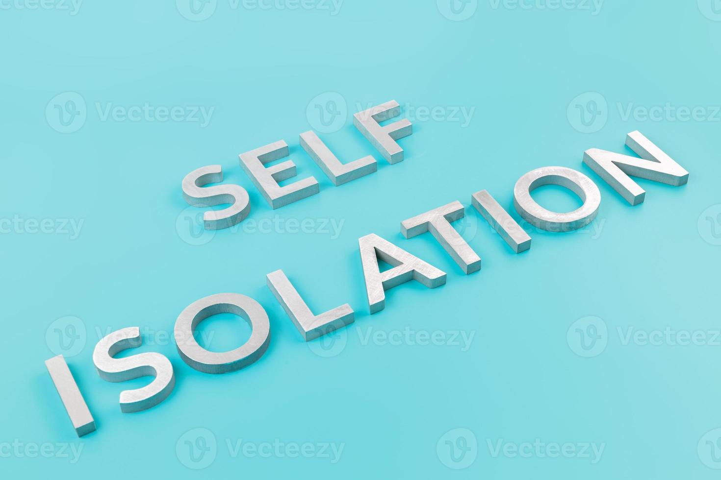 the words self isolation laid with silver metal letters on pastel blue background with diagonal slanted perspective photo