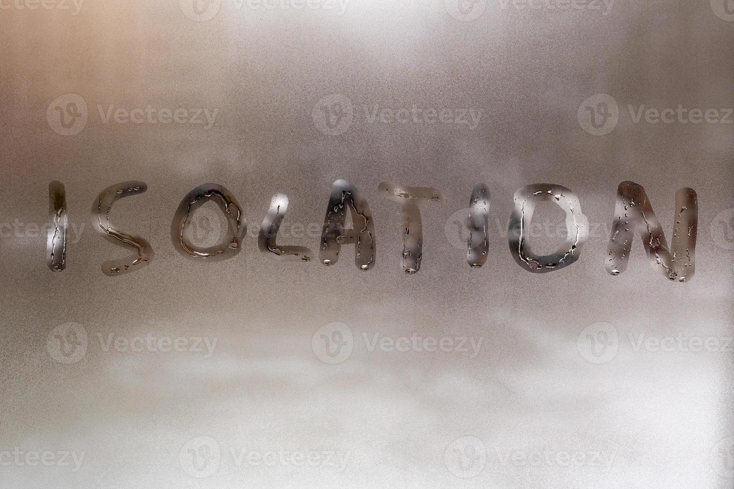 the word isolation handwritten on wet window glass at cloudy weather - close-up with selective focus and background blur photo