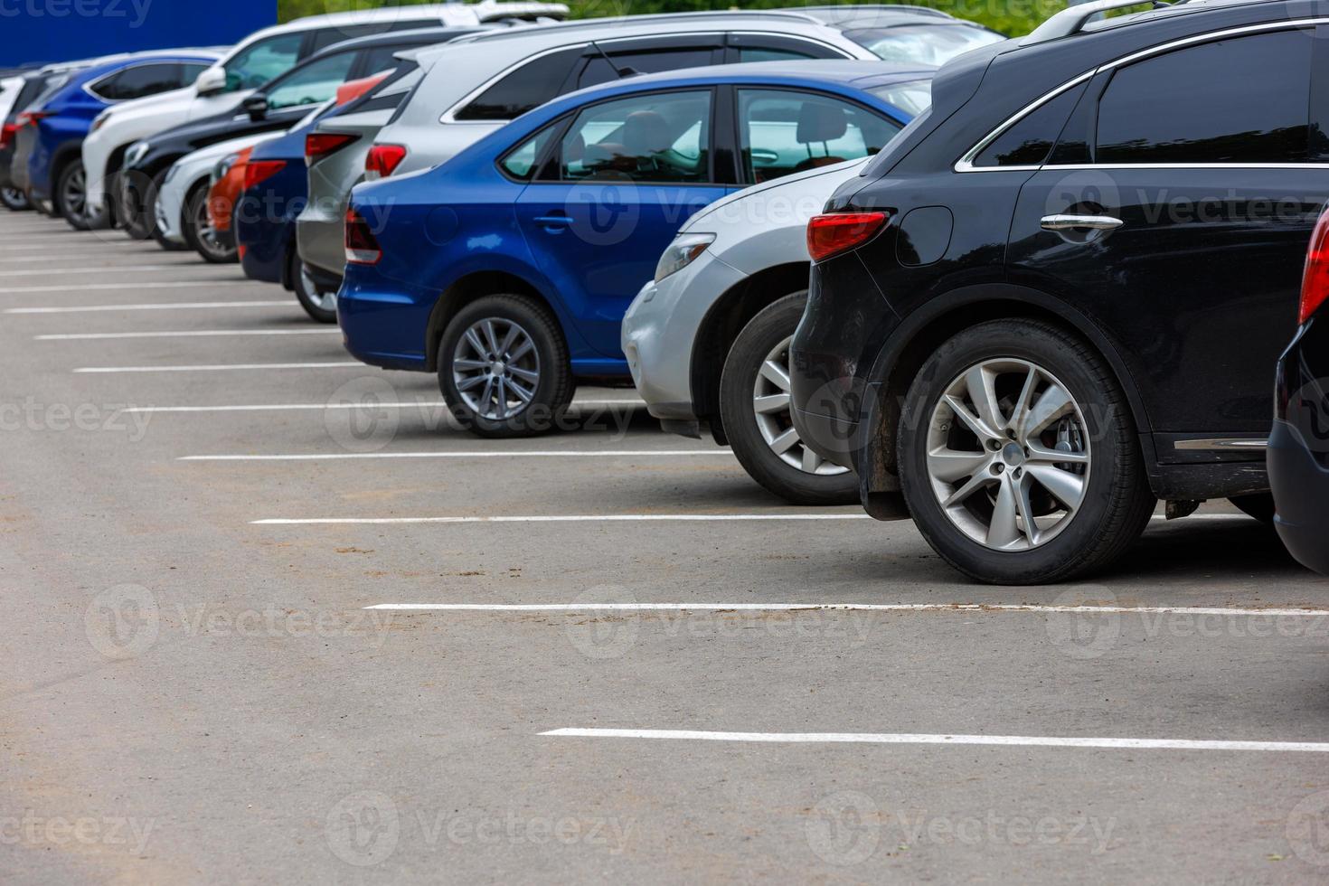 row of different color cars on asphalt parking lot at cloudy summer day photo
