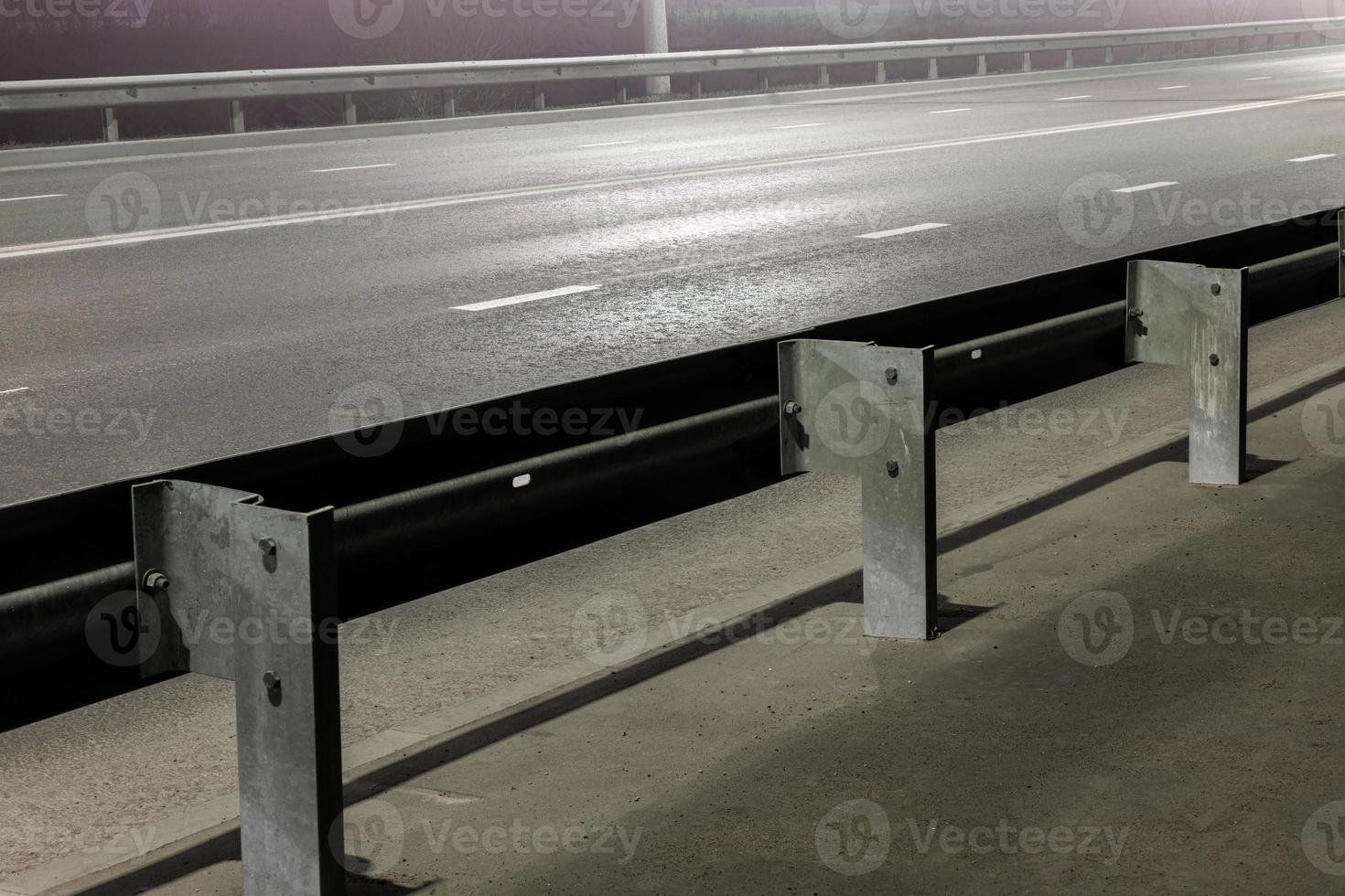 illuminated empty foggy night road with rigid guardrails photo