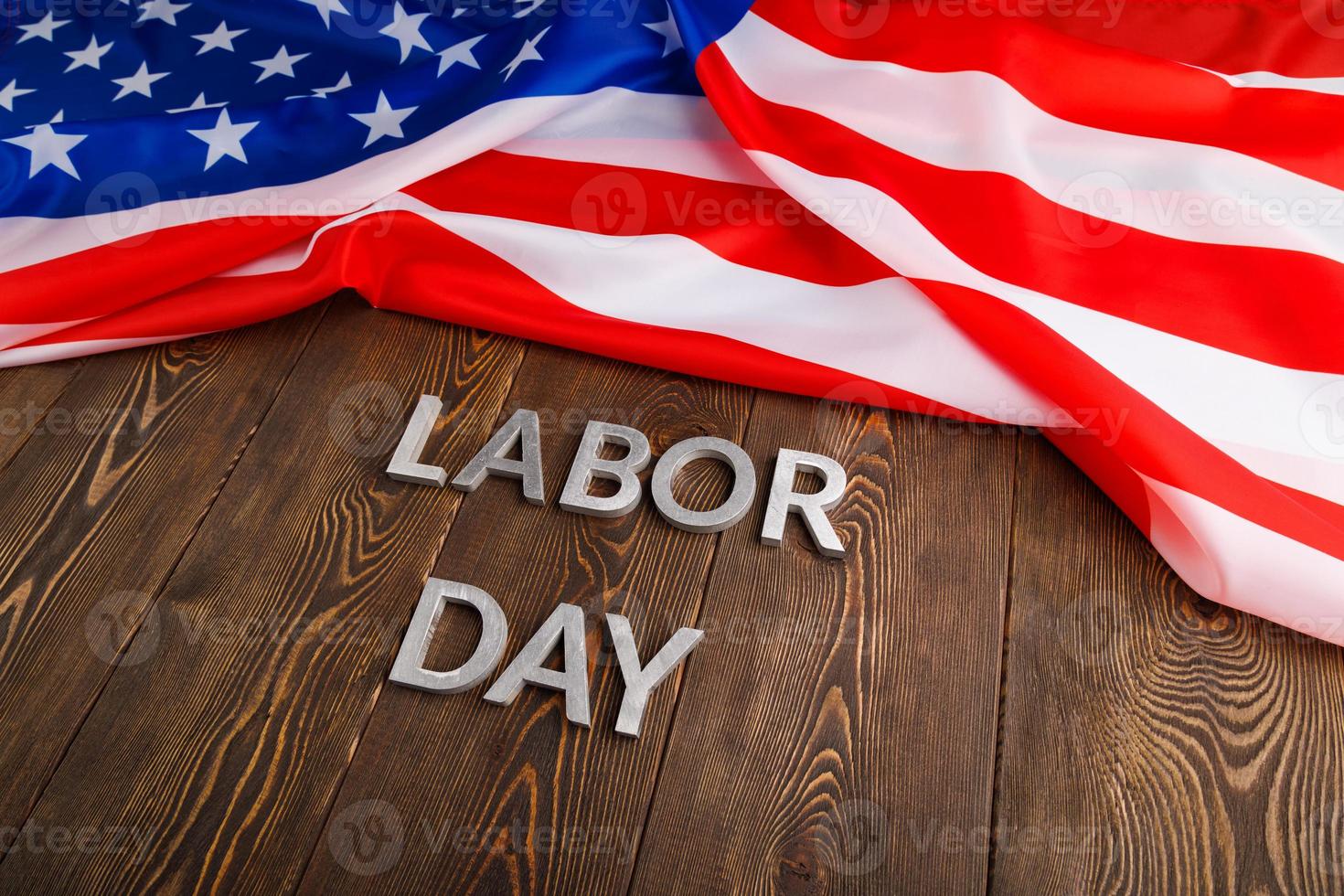 words labor day laid with silver metal letters on wooden surface with crumpled USA flag on left side photo