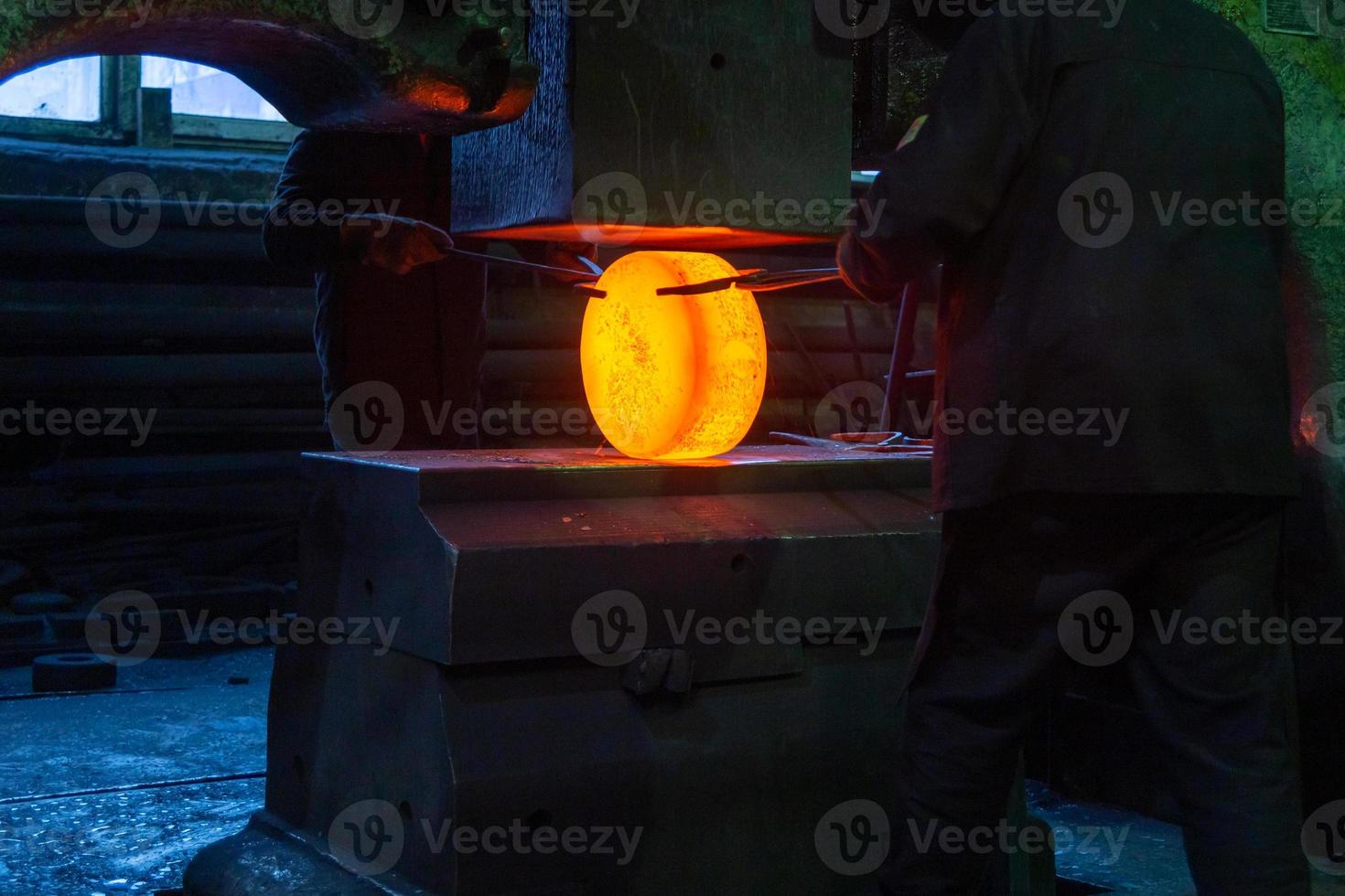 close-up picture of hot steel manual forging process with big mechanical hammer machine photo