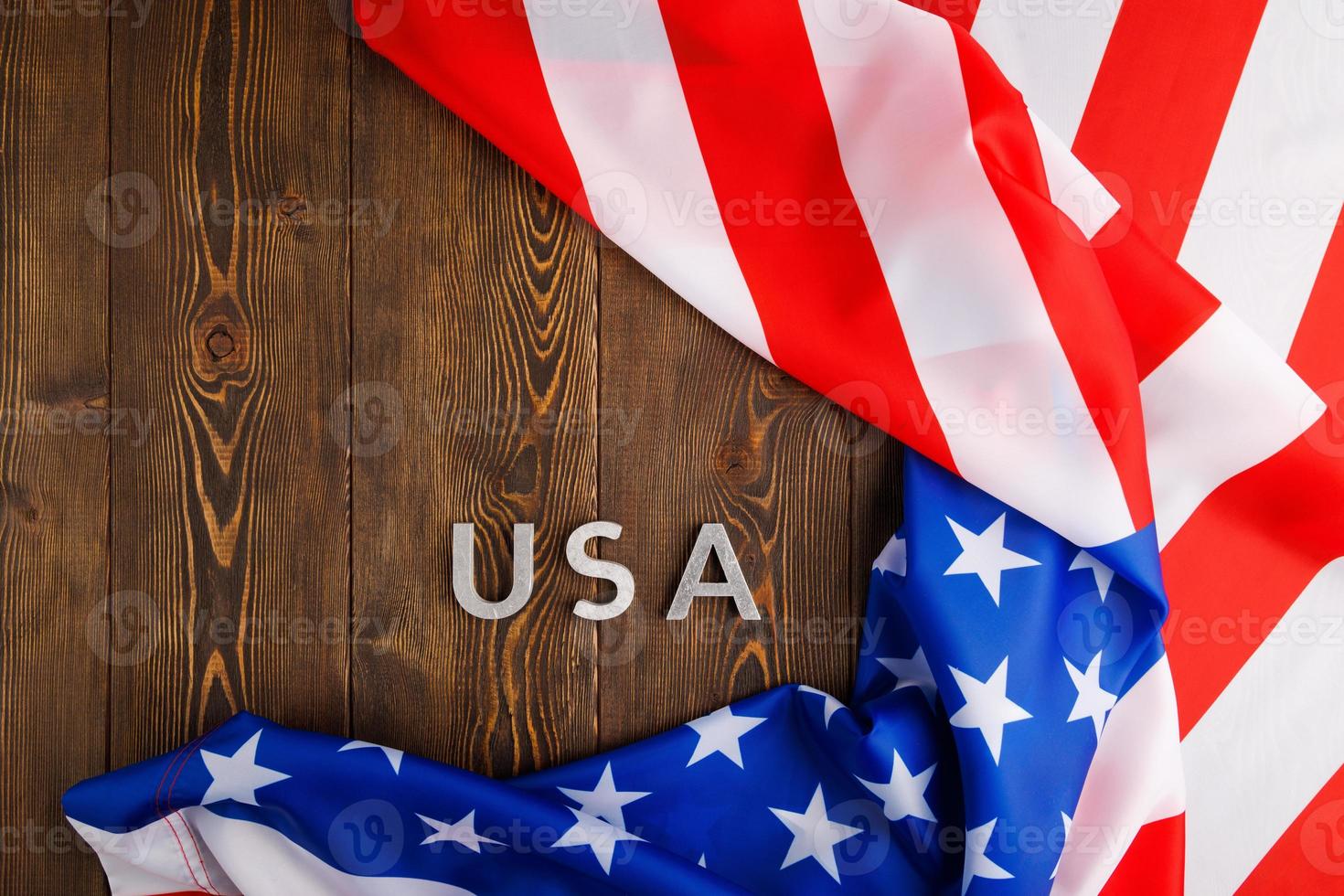 la palabra ee.uu. colocada con letras de metal plateado en la superficie de una tabla de madera bajo la bandera arrugada de los estados unidos de américa foto