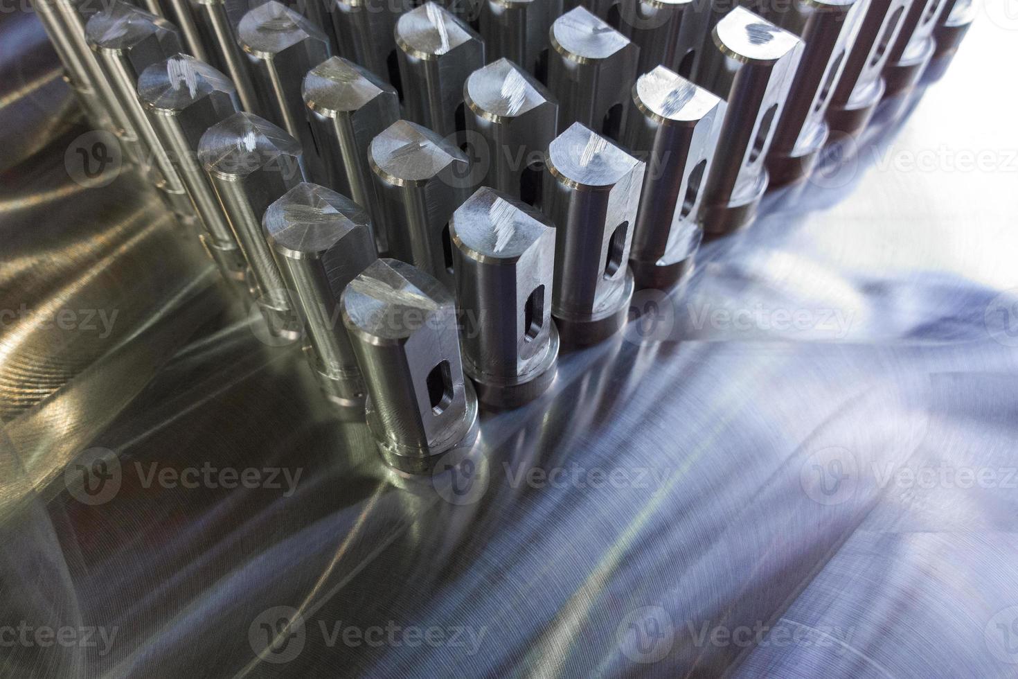 Batch of shiny metal parts after cnc turning and milling on flat milled surface with selective focus. photo