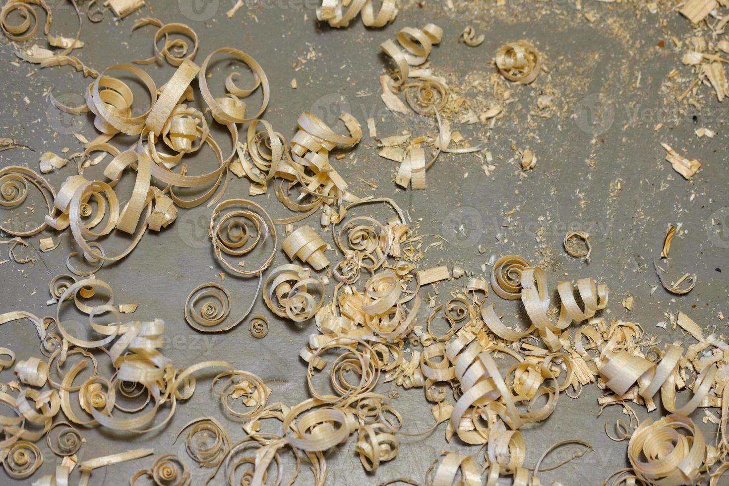 a small pile of wood shavings on a gray linoleum floor photo