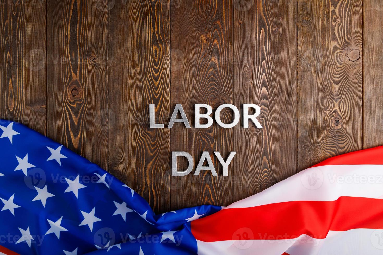 words labor day laid with silver metal letters on wooden surface with crumpled USA flag on bottom side photo