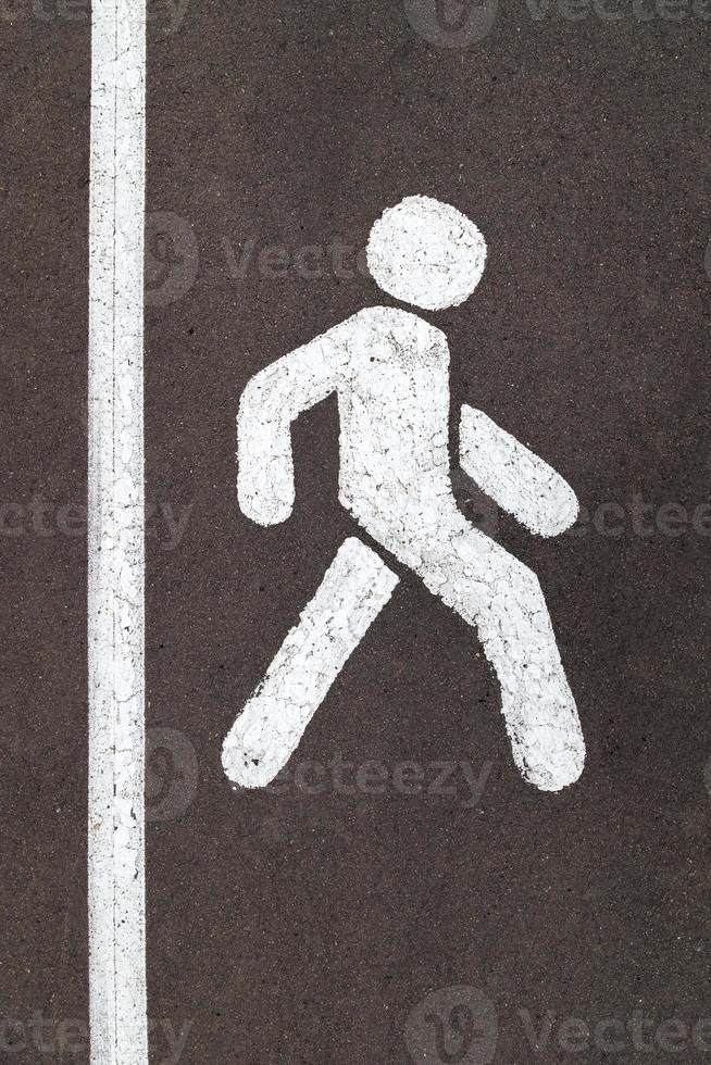 White walking person street sign on grey city asphalt road with vertical stripe photo