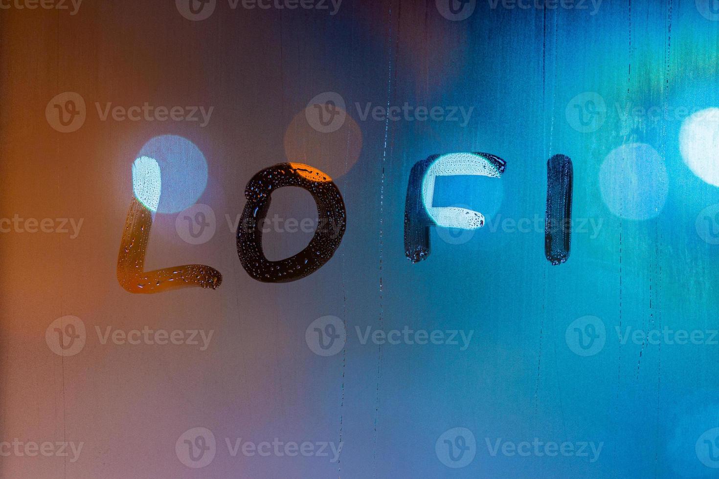 the word lofi written by finger on night wet window glass, blue and orange colors photo