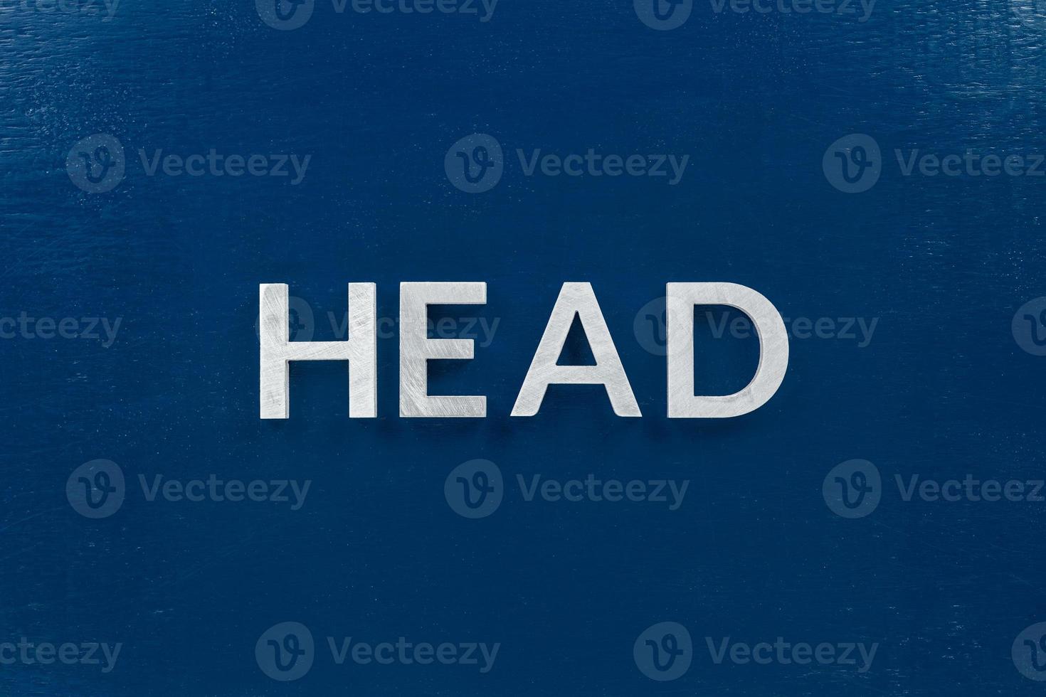 the word head laid with silver metal letters on classic blue painted board background photo